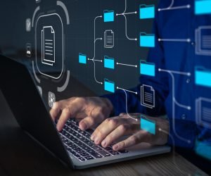 Document Management System (DMS) being setup by IT consultant working on laptop computer in office. Software for archiving, searching and managing corporate files and information. Business processes